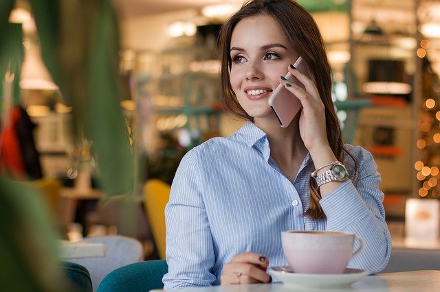mulher sentada falando no celular e tomando café